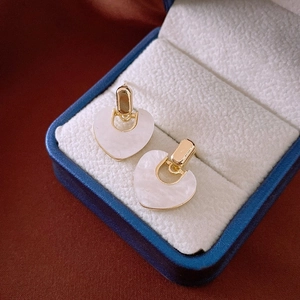 Détail de boucles d'oreilles cœur dorées vintage avec incrustation de nacre blanche