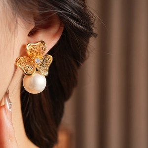 Detail of vintage gold flower earring with zircon center and white pearl on model