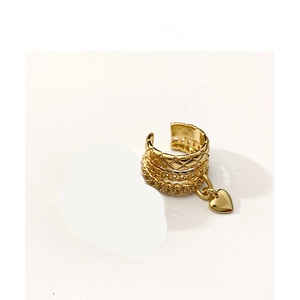 Detailed view of wide gold ear cuff with quilted patterns and heart pendant
