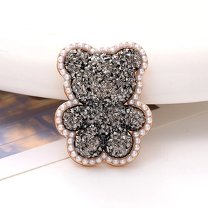 Macro view of bear-shaped charm with gray rhinestones and white pearl border detail