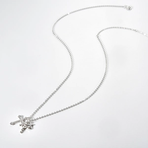Detail of silver triple layered cross pendant with sparkling stones and rivet texture
