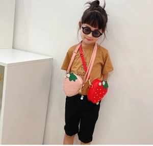 Detail of red and pink strawberry-shaped crossbody bags with gold stud embellishments