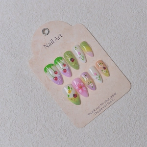 Detailed view of 3D almond press-on nails with strawberry, ladybug, and flower designs