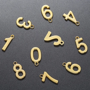 Polished 18K gold plated number charms from zero to nine on textured surface