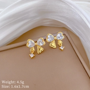 Dettaglio orecchini a fiocco dorati con zircone a cuore bianco, misura 1.6x1.7cm, peso 4.5g