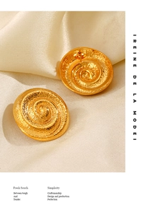 Gros plan de boucles d'oreilles spirales dorées à texture martelée sur du satin