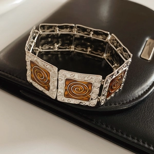 Detailed view of vintage silver metal square links with brown enamel spiral patterns