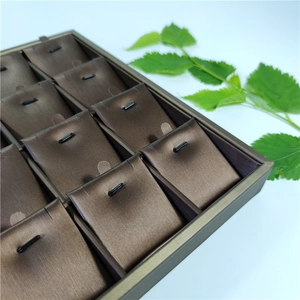 Detail of 24-grid jewelry display tray with bronze metal frame and brown satin padding
