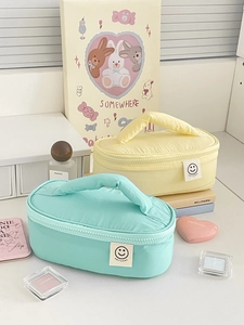 Detail view of quilted smiley face cosmetic bags in mint green and pale yellow