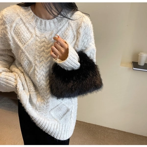 Detail of black faux fur handbag with plush texture paired with a beige knit sweater