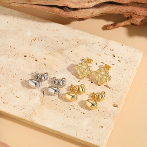 Detail view of gold and silver geometric woven square and oval stud earrings on stone
