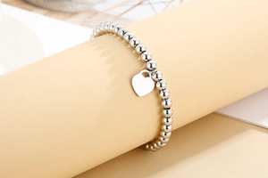 Close-up of 4mm stainless steel beaded bracelet with polished heart pendant on display