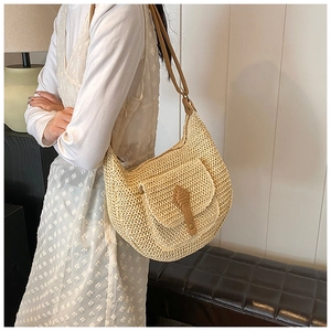 Detailed view of woven straw shoulder bag with brown leather strap and unique buckle