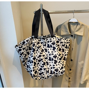Dettaglio di una grande borsa tote con stampa mucca bianca e nera e tracolla nera