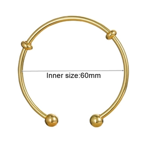 Detail view of a 60mm inner diameter golden knot open bangle bracelet with ball ends