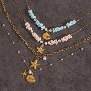 Collana a strati dorata con stella marina, conchiglia, perle e pietre colorate su pietra