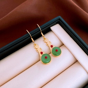 Vue détaillée des boucles d'oreilles Pipa avec jade vert et finition dorée en boîte à bijoux