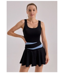 Close-up of the pleated hem and contrast blue waist detail on the black sports dress