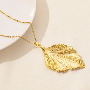Macro detail of golden leaf pendant with fine veins and elegant texture on thin chain