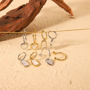 Gold and silver stainless steel earrings with geometric shell pendants on beige background