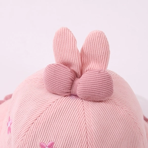 Dettaglio di un cappello da pescatore rosa in velluto con orecchie di coniglio e ricami