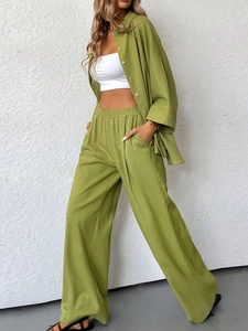 Close-up of olive green linen texture on a loose shirt and wide-leg trousers set