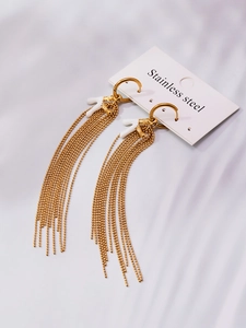 Detail view of long gold bead tassels and white coral element on stainless steel earrings