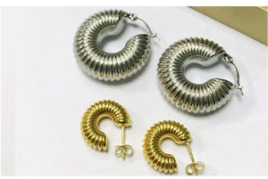Close-up of trendy chunky ribbed metal hoop earrings in silver and gold finishes detail.