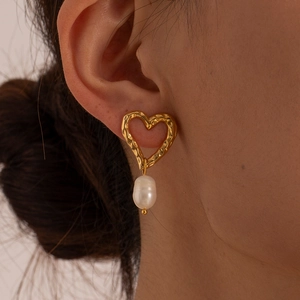 Detail of baroque pearl earring with irregular heart-shaped gold textured stud on model