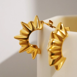 Macro shot of 18K gold sunburst C-shaped earrings showing fine metal texture and butterfly back