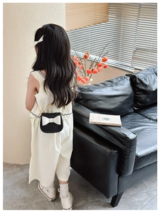 Detail of kids black bow bag featuring white ribbon and elegant pearl handle straps