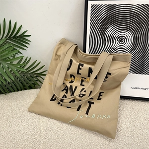 Detail of khaki canvas tote bag featuring black lettering and elegant embroidery accents