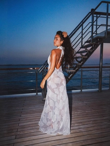 White sheer halter maxi dress with burnout leaf pattern on a yacht deck at sunset