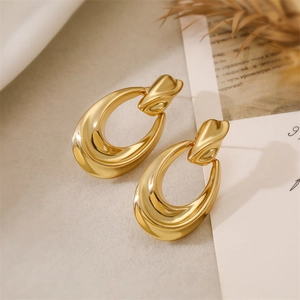 Detailed view of large gold-tone irregular wavy metal earrings with polished surface