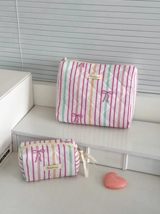 Detail of two-piece quilted striped makeup bags with pink bow prints and brand label