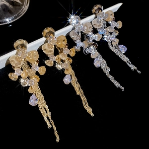 Macro shot of silver needle tassel earrings with zircons and floral pendants