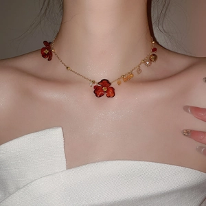 Detail of acrylic floral necklace with red petals and golden chain on model's neck