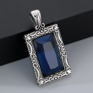 Gros plan d'un pendentif rétro en acier avec pierre bleue et motifs ciselés baroques