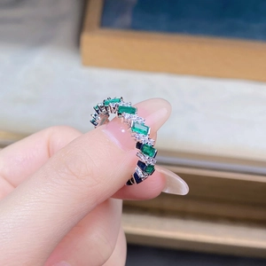 Macro shot of silver ring with alternating emerald cut green gems and small clear round stones