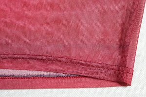 Macro detail of red mesh fabric showing precise double-stitching and woven texture