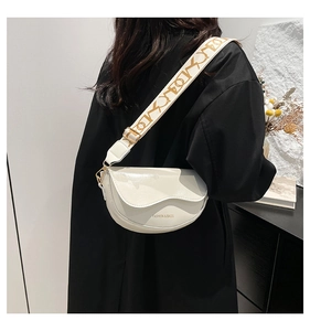 Detail of white saddle bag with wide woven strap and gold hardware on model