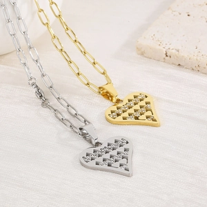 Detailed view of gold and silver heart necklaces with pave crystals on textured fabric