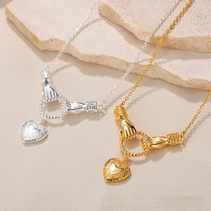 Detail of vintage heart charms and hand-clasp rings in gold and silver finish