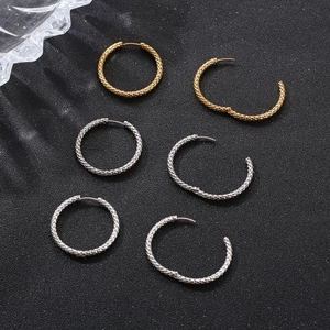 Dettaglio di orecchini a cerchio in acciaio al titanio oro e argento con trama a serpente