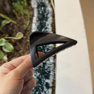 Detail view of large matte black triangular hair claw clip showing textured resin surface