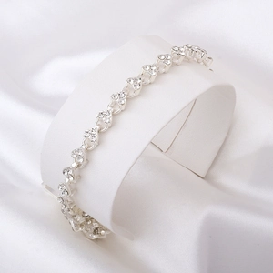 Détail d'un bracelet cœur argenté avec cristaux sur support de bijoux et soie blanche