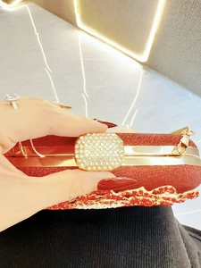Detail of red glitter evening clutch bag with gold rhinestone clasp and metal frame