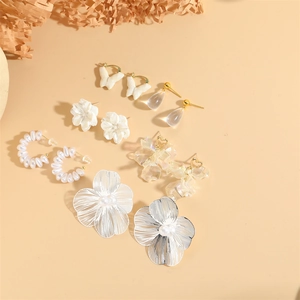 Floral alloy and pearl drop earring set with crystal waterdrop charms on beige background