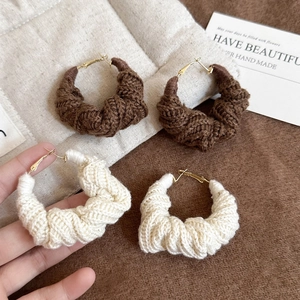 Détail de boucles d'oreilles créoles tressées en laine marron et beige avec base dorée chic