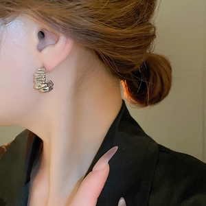 Detailed view of silver minimalist multi-layer hoop earrings with a pleated texture on model